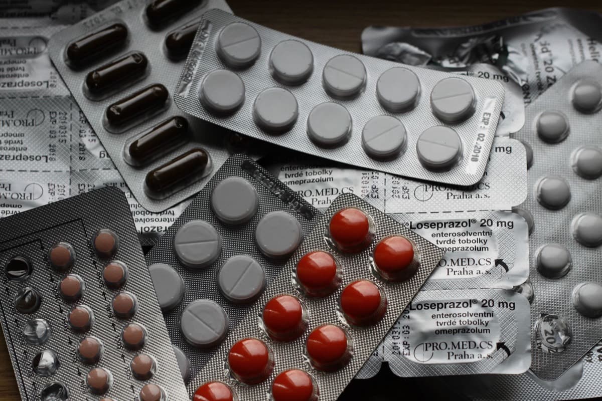 Close-up of assorted supplement capsules and tablets scattered on a white surface